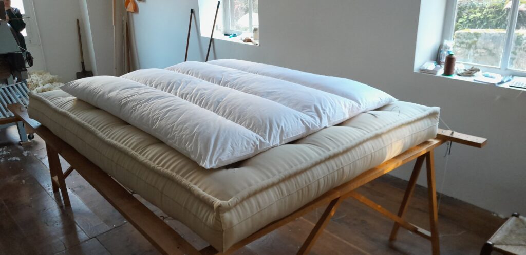 Édredon naturel en laine et duvet sur lit habillé de tissus naturels